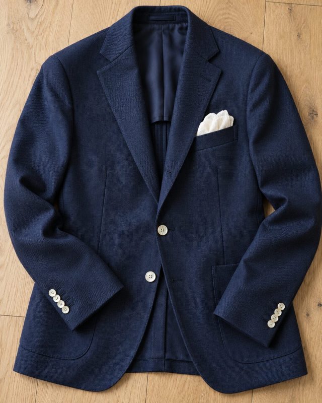 Blazer azul marino con botones de nácar sobre suelo de roble